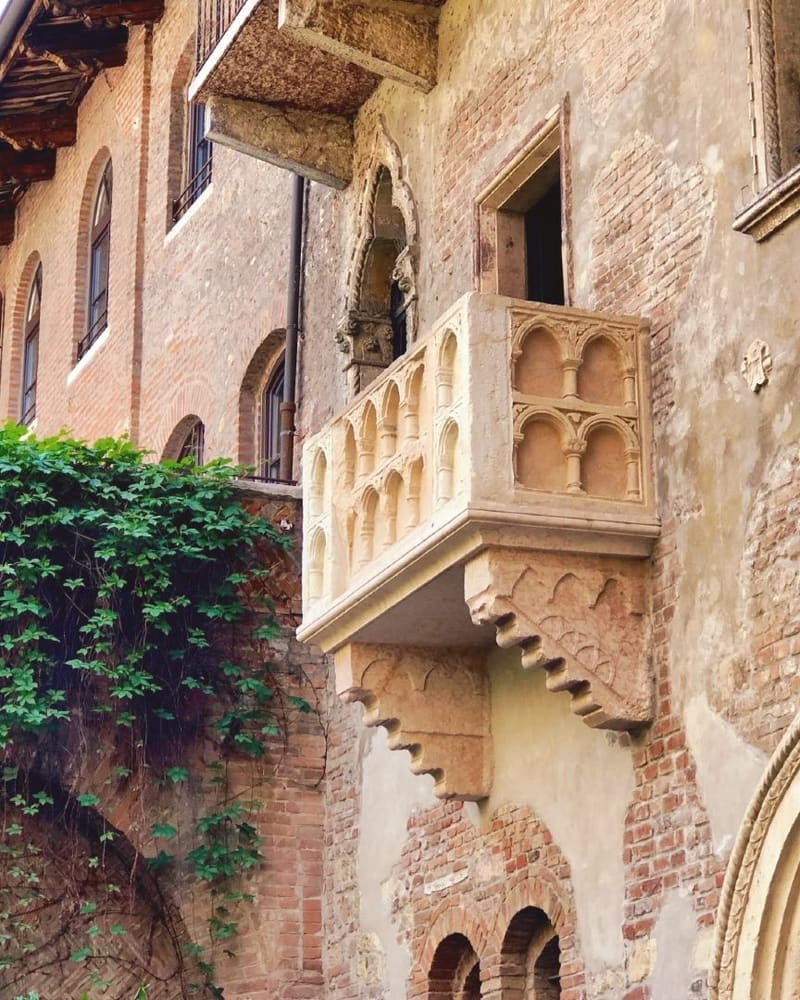 il balcone in pietra della Casa di Giulietta sulla parete in mattoni, con l'edera a sinistra