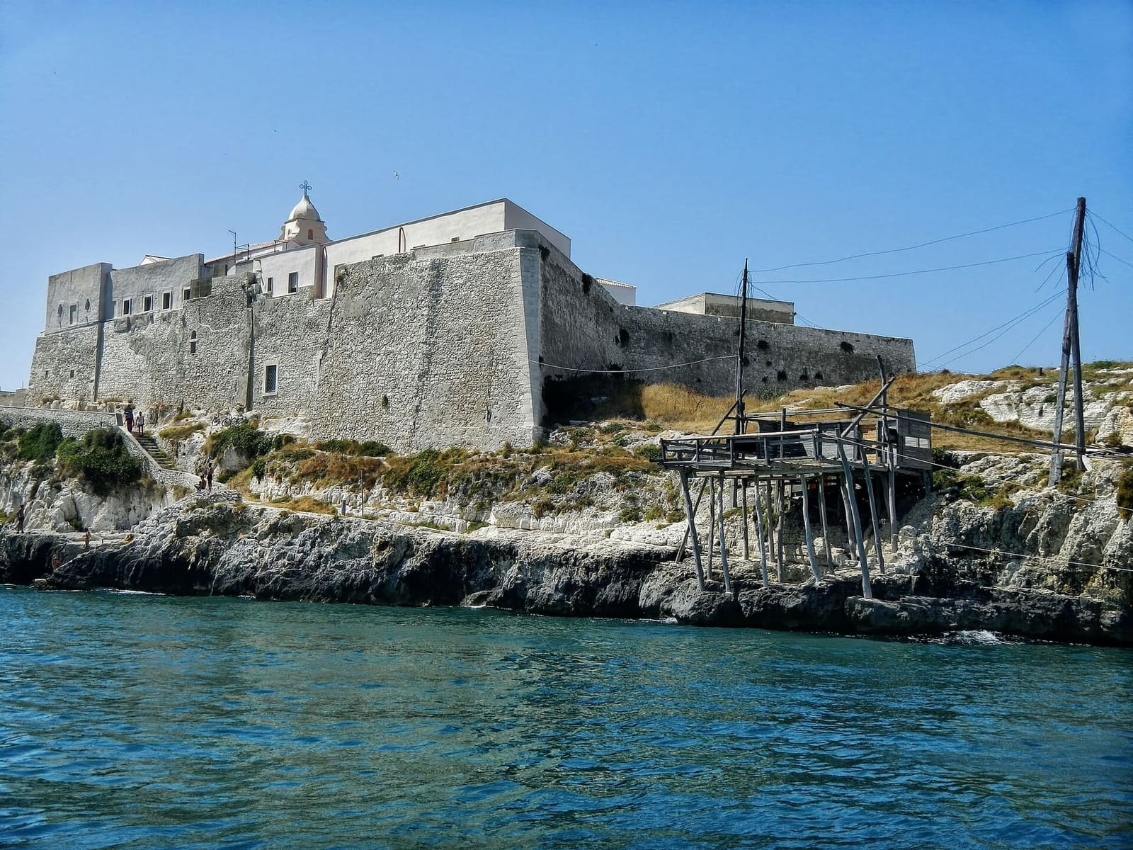 il Castello Svevo sulla roccia, visto dal mare, con un trabucco sotto